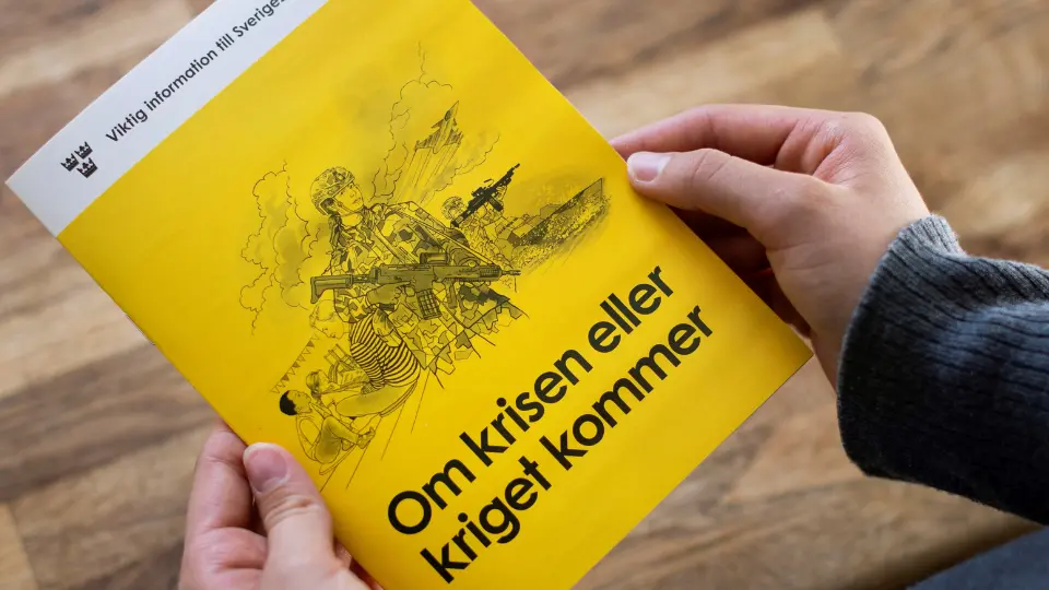 Någon håller broschyren "om krisen eller kriget kommer" i händerna