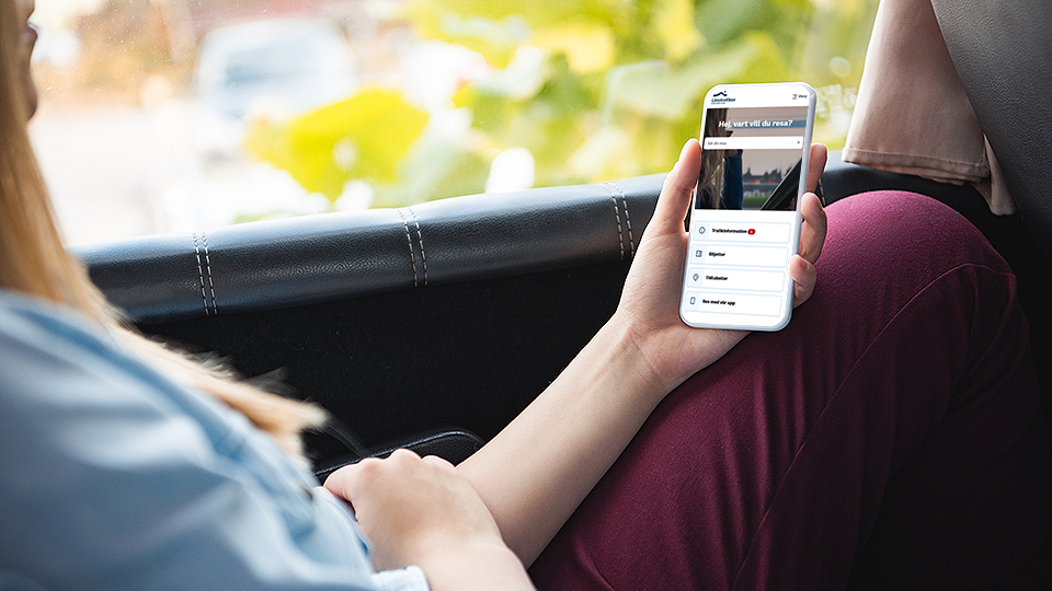 person sitter på bussen med mobiltelefon i hand