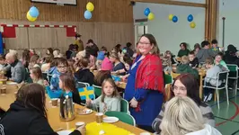 Elever sitter och fikar i en midsommarsmyckad gympasal